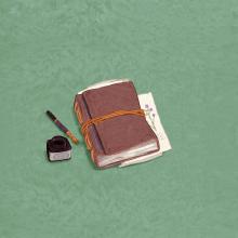 Livre relié en cuir, fermé à l'aide d'un cordon. Des pages illustrées de fleurs dépassent du livre. Un encrier et une plume sont posés à côté du livre.